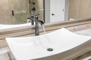 Vessel sink with water running in neutral tan bathroom