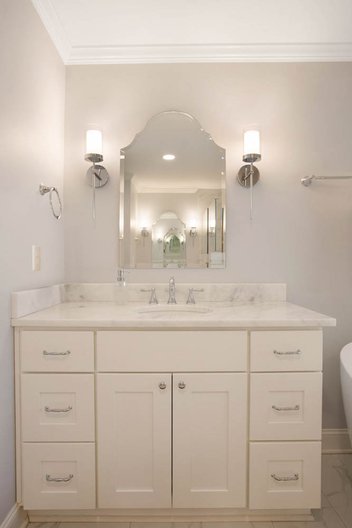 White primary bath vanity with crown frameless beveled mirror