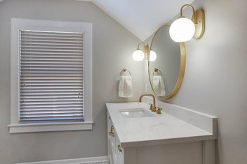 Neutral bathroom with white vanity, round sconces and gold fixtures