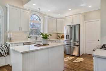 Traditional Southern kitchen with white cabinets, tan subway tile, and hardwood floors