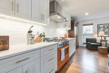 White kitchen with lighting under cabinets and orange range
