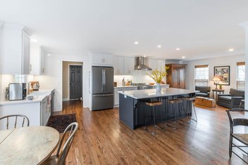 White kitchen with navy island and hardwood floors