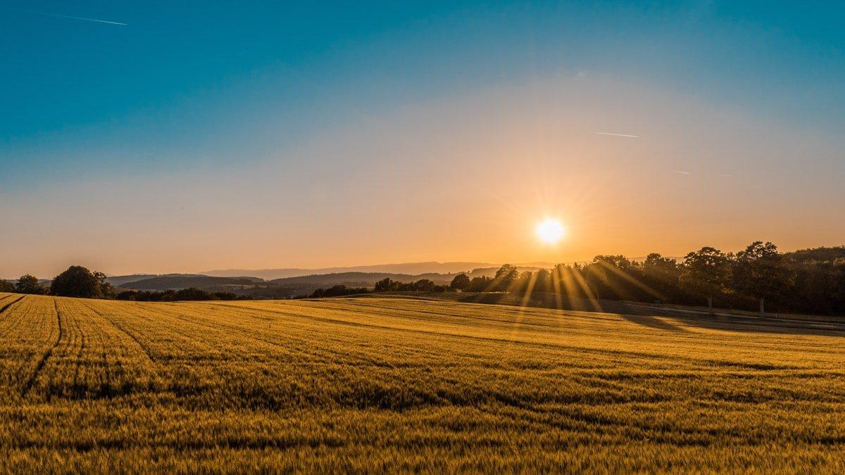 Dramatic golden light rays breaking through clouds over a rural landscape