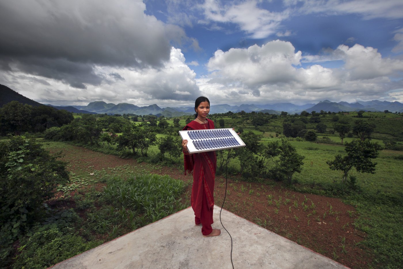 South Asian woman outdoors, holding small solar array