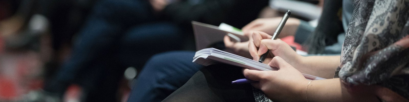 Closeup of hands taking notes at a conference