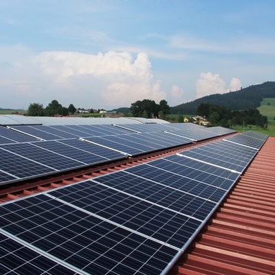 Slanted view of rooftop array, steel roof, green hills