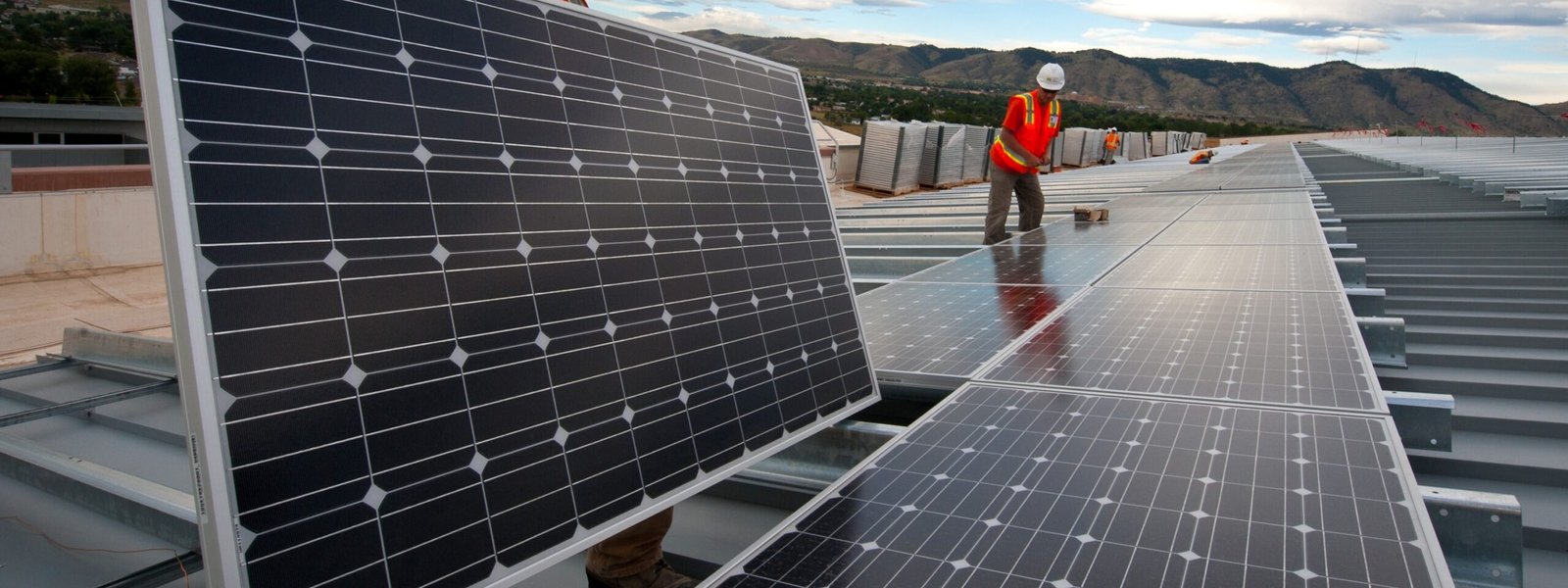 Workers handling panels on large rooftop installation