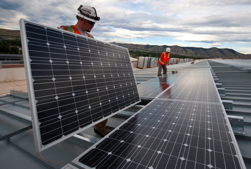 Workers handling panels on large rooftop installation