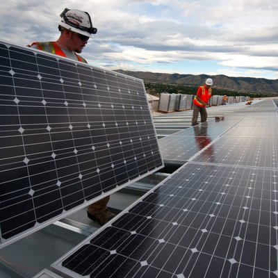 Workers handling panels on large rooftop installation