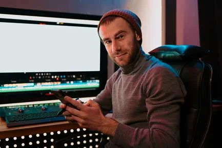 male-video-editor-sitting-at-his-computer-using-ph-2021-09-01-10-46-00-utc