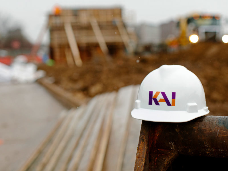 KAI Enterprises Construction Hat in front of a Construction Site