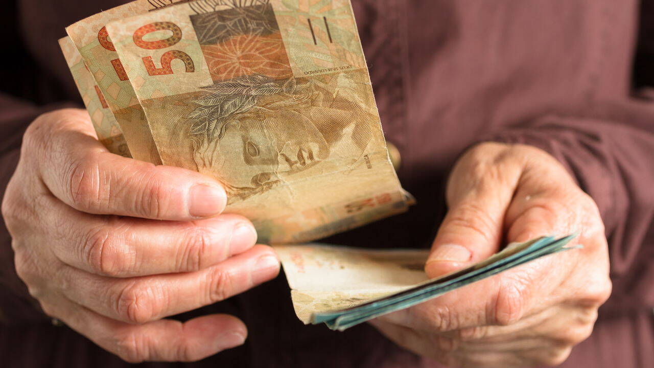 Brazilian currency: Real. Front view senior person holding bills