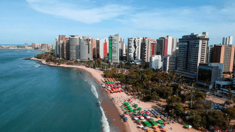 Vista aérea da Praia de Meireles, em Fortaleza (CE), com suas coloridas barracas à beira-mar e modernos edifícios à beira da orla