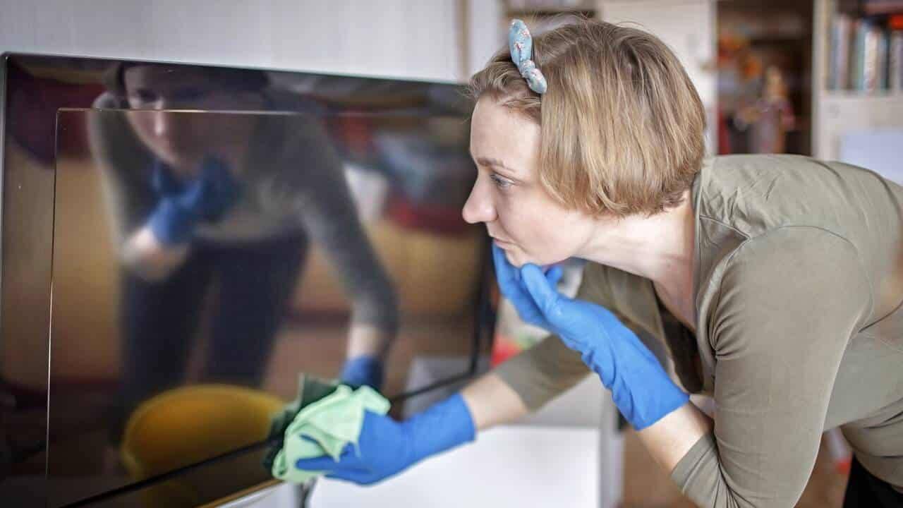 Mulher limpando tela de televisão