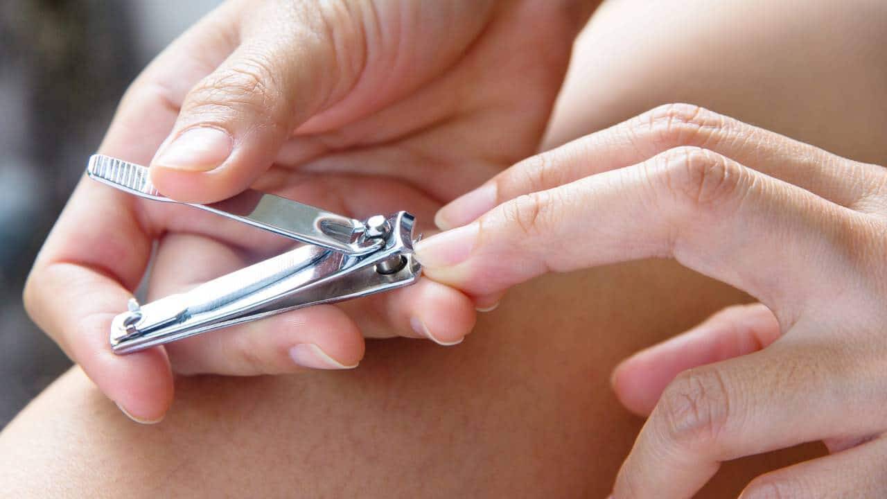 Pessoa cortando as unhas com cortador de unhas