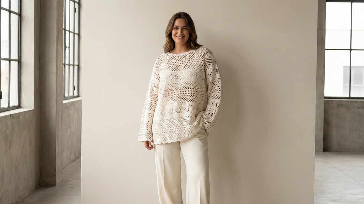 Mulher sorrindo em estilo contemporâneo urbano usando blusa de crochê artesanal em tom off-white, confeccionada em fio de algodão, modelagem moderna levemente oversized
