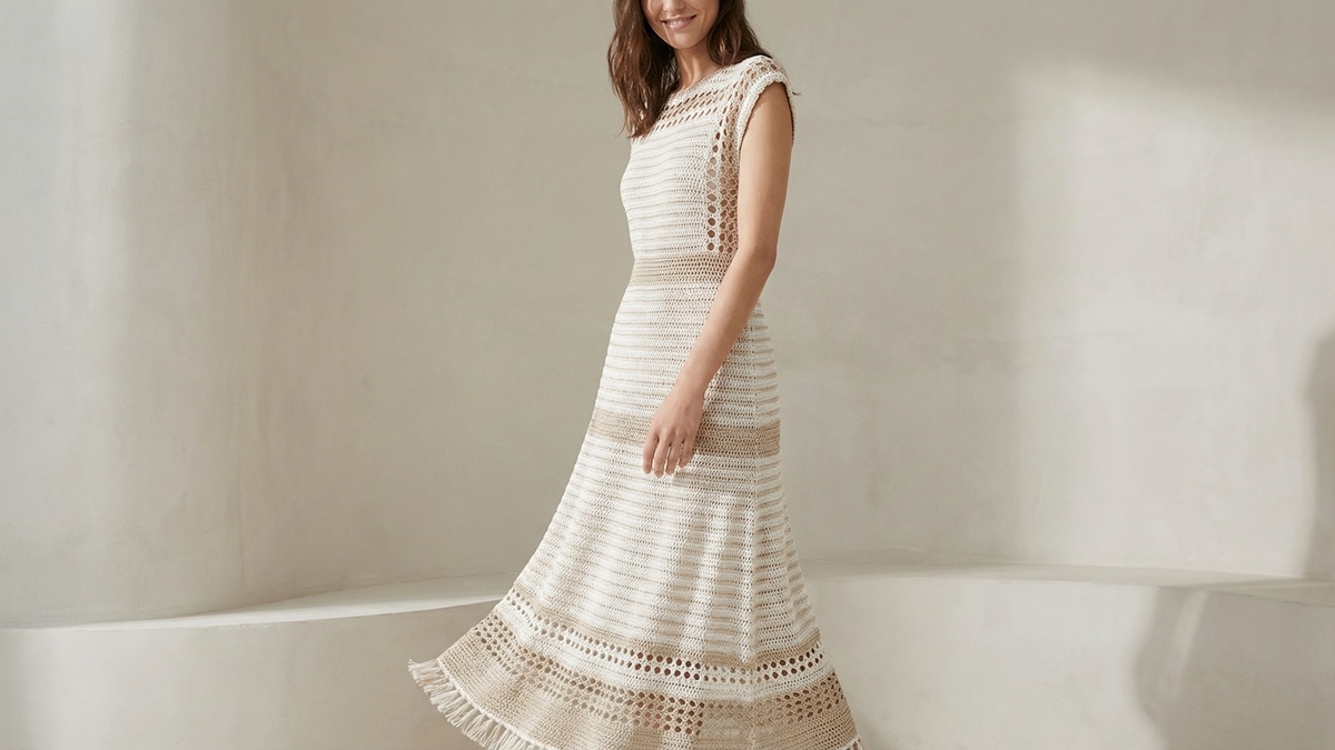 Mulher usando vestido de croche em tons claros com lurex, modelagem elegante e estetica fashion verao