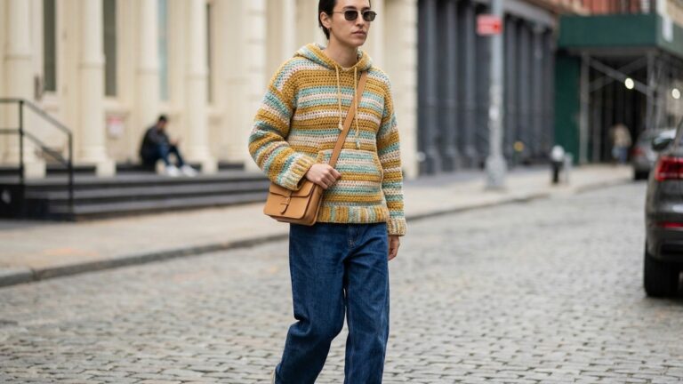 Look street style com blusa de croche artesanal com capuz em cores modernas combinada com jeans e acessorios neutros