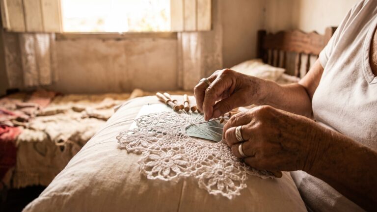 Maos experientes de rendeira nordestina trabalhando em renda de croche tradicional, mostrando a tecnica artesanal ancestral brasileira