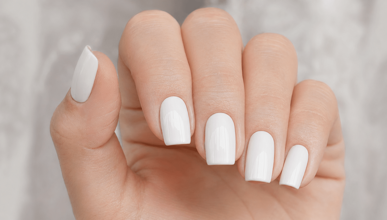 Unhas com esmalte branco perfeito, mostrando o acabamento uniforme e brilhante