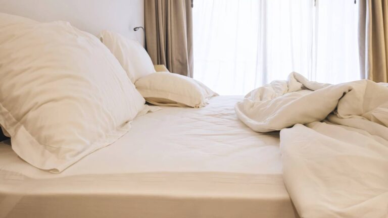 Cama desarrumada com travesseiros e edredom