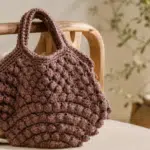 Bolsa de crochê castanha apoiada sobre uma cadeira de madeira,