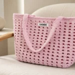 Bolsa de crochê rosa estruturada em ambiente minimalista com poltrona bege