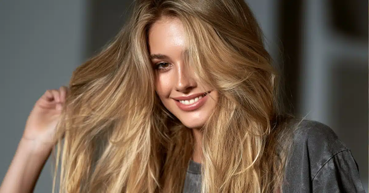 Mulher com cabelo loiro em tom natural e quente, com mechas douradas e aspecto saudável.