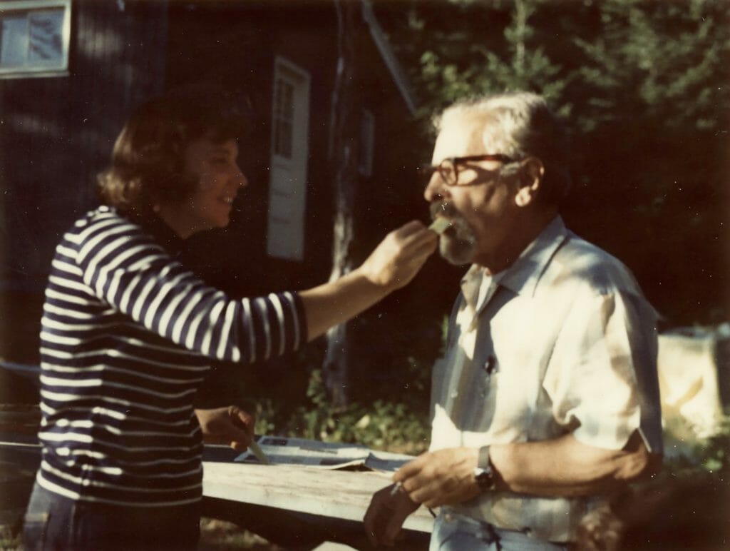 Woman feeds man some cheese. In country