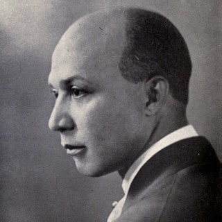 A grayscale side-profile photo portrait of George Washington Ellis. He is a light-skinned Black man whose buzzcut hair has receded half-way across his head. His gaze is intense. yet it still feels distant.