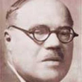 A sepia-toned portrait photograph of Francisco Garcia Calderon Rey. He is wearing circle-shaped glasses and he has a narrow moustache. His hair is neatly combed over. Photo Credit: Unknown. Photo Source: Wikimedia Commons.