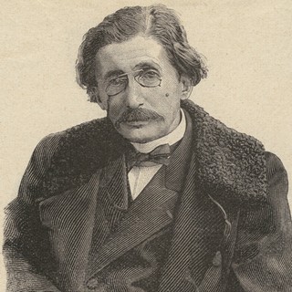 A wood-carved portrait of Gabriel Tarde. He is wearing a suit and coat with fur around the collar. He is wearing small glasses that are attached to a single chain. he has a full, dark-colored mustache.
