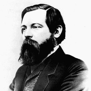 A gray-scale photo portrait of Friedrich Engels. He has a very large, but neatly-manicured beard. His hair is also neatly combed. He is wearing a suit and facing to the left. Year: 1868. Photographer: George Lester. Source: https://en.wikipedia.org/wiki/Image:Engelss56fe1.jpg