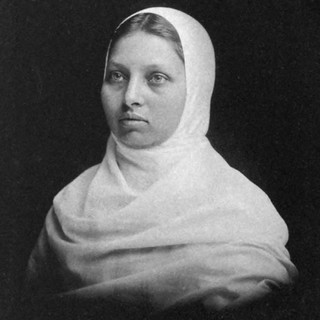 A grayscale photo portrait of Pundita Sarasvati. She is wearing a light-colored headscarf that covers down past her shoulders. She is looking off into the distance. Photo Credit: photographer unknown. Photo Source: Wikimedia Commons.