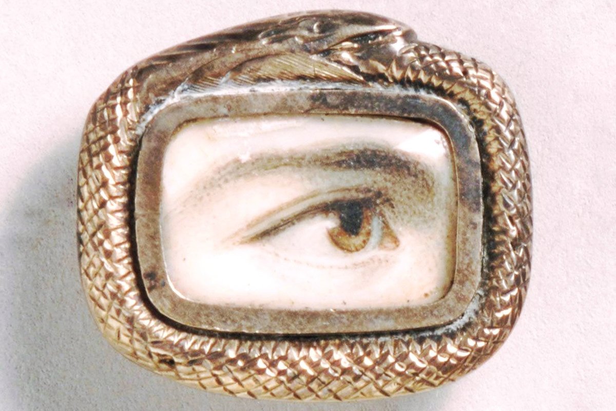 A miniature watercolor painting of a single human eye, set in a gold brooch bordered by a coiled snake.