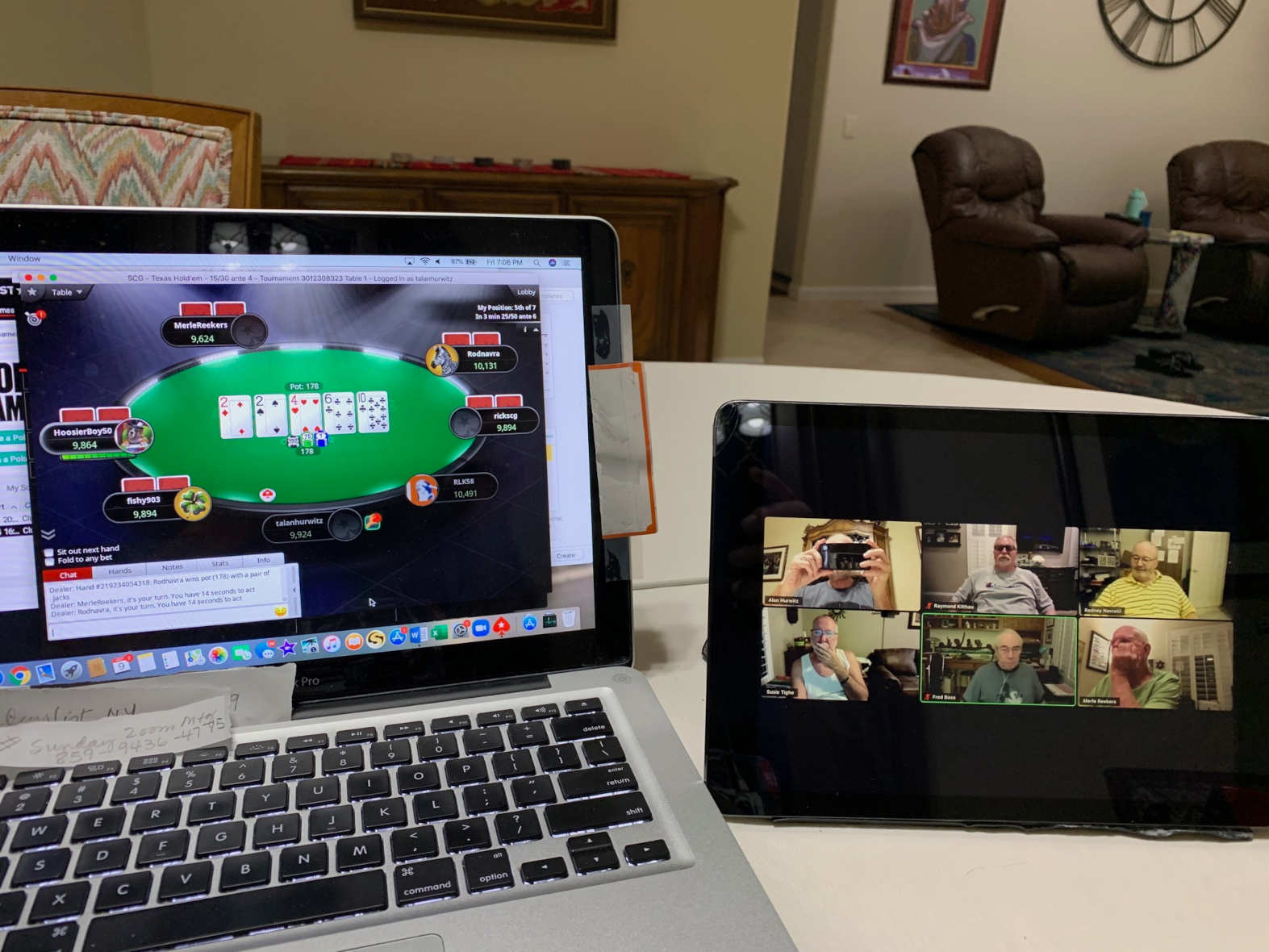 A laptop computer is open on a table. On its screen is a green oval with five cards: a two of diamonds, a two of spades, a four of hearts, a six of clubs, and a ten of clubs. Next to the laptop is a videophone with six frames. In the frames are six white older men with their names in the lower left corner of the frames.