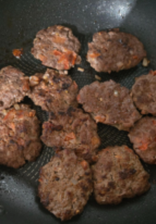 Seasoned, pan-fried ground beef patties in a pan