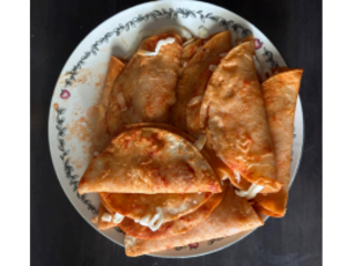 A pile of entomatadas on a plate (traditional Mexican dish consisting of corn tortillas that are lightly fried, dipped in a tomato-based sauce, and filled with ingredients, in this case cheese)