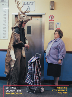 Marcus Coates wearing a deer costume stands near an elevator, speaking to an older woman with a shopping trolley.