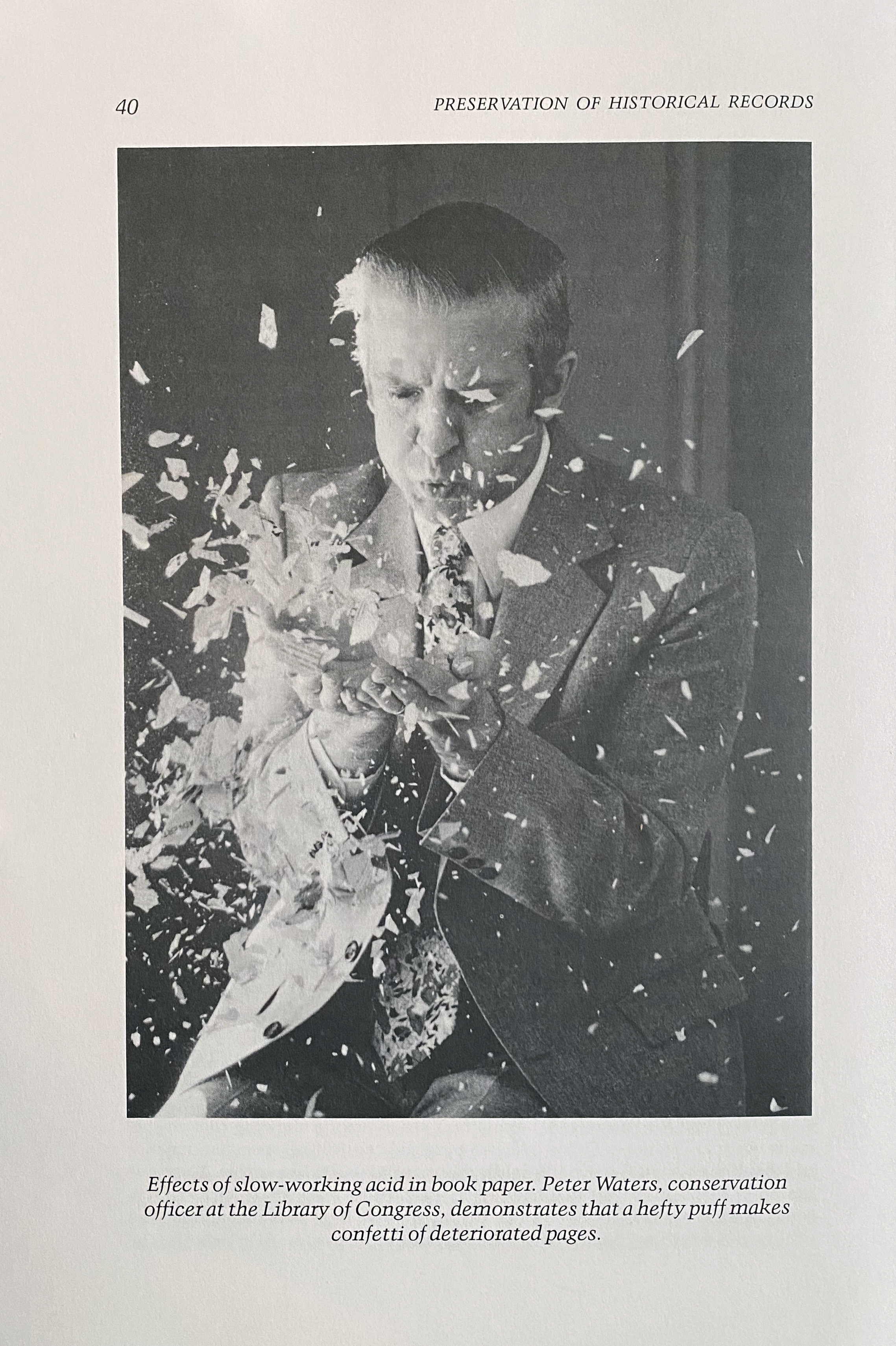 Photograph of conservator Peter Waters surrounded by paper fragments.