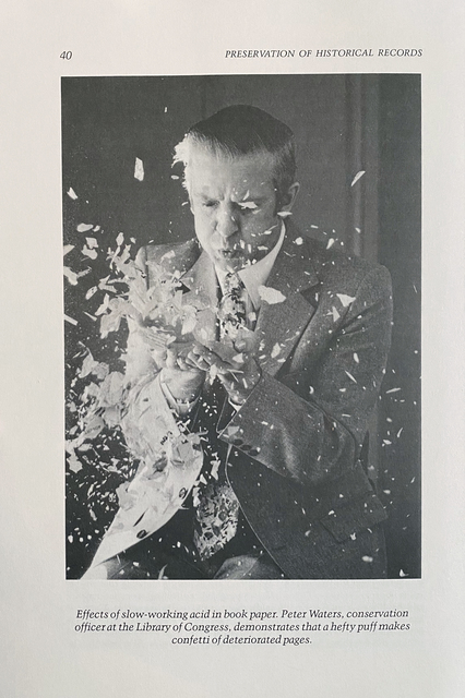 Photograph of conservator Peter Waters surrounded by paper fragments.