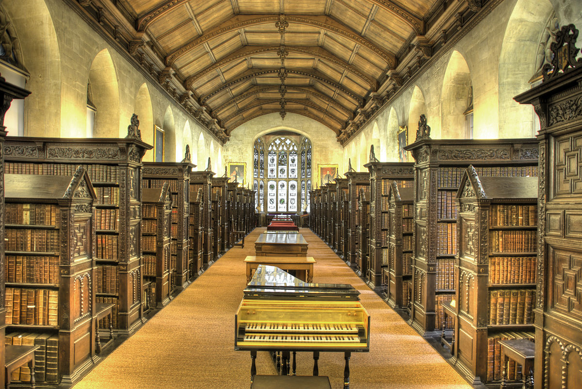 A photograph of the length of the Old Library at St John’s College, Cambridge University, showing many of the library’s 42 bookcases lined perpindicularly against the long north and south walls.