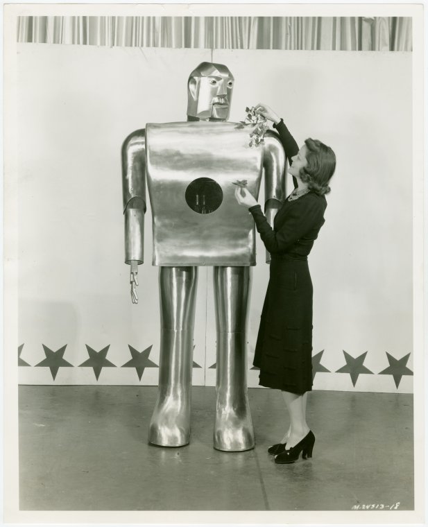 Photograph of a woman showing roses to Elektro the robot at the 1939 New York World's Fair.