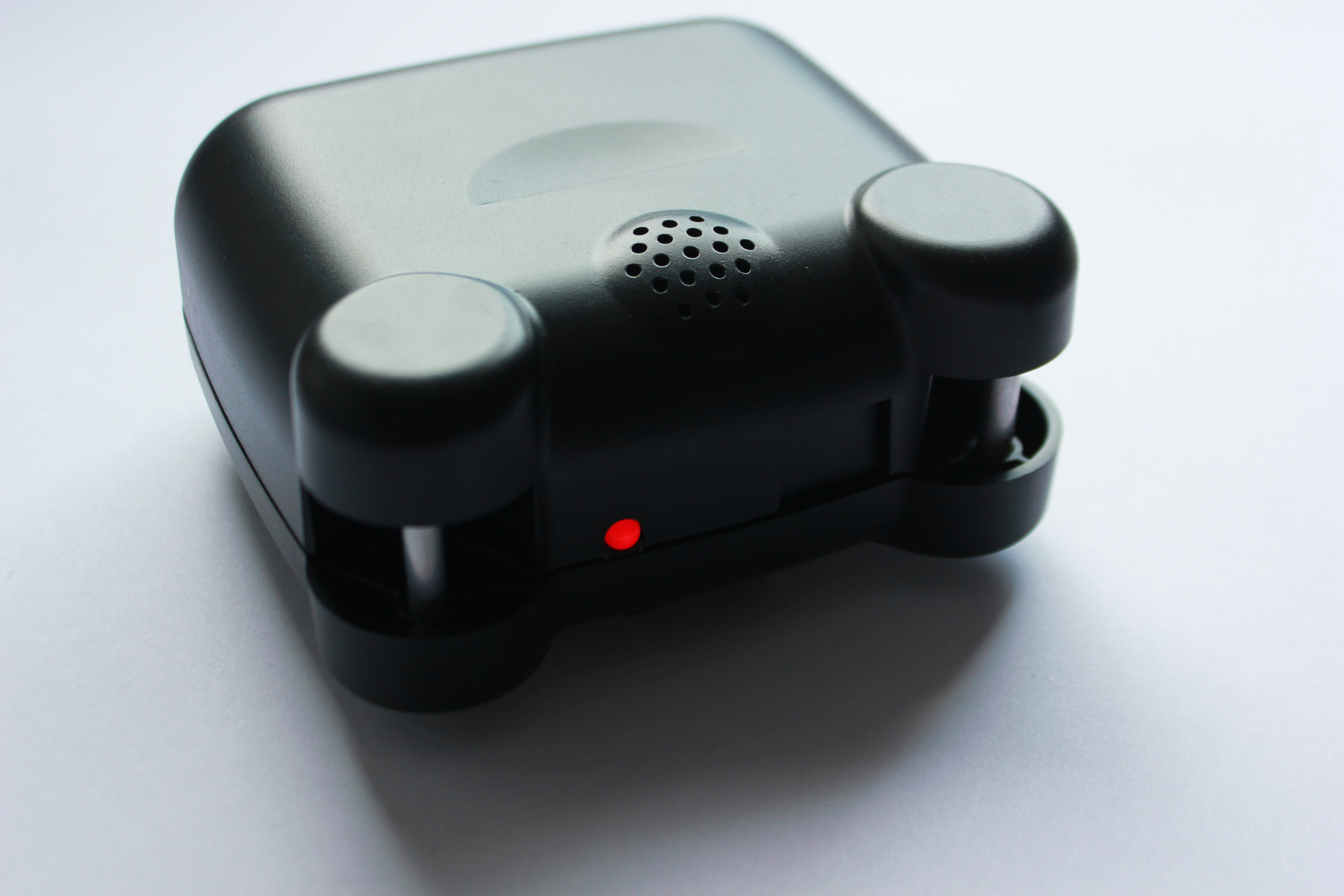 Small black square casing with rouded edges, red light, and vent with small, circular passages.