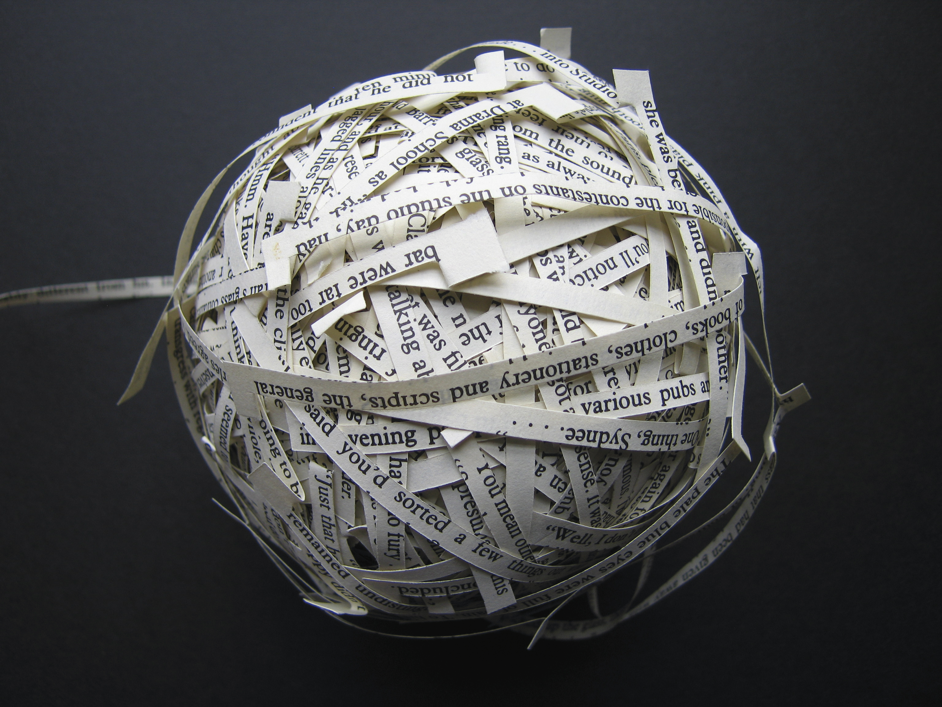Photograph of a string of text cut from a book and rolled into a ball