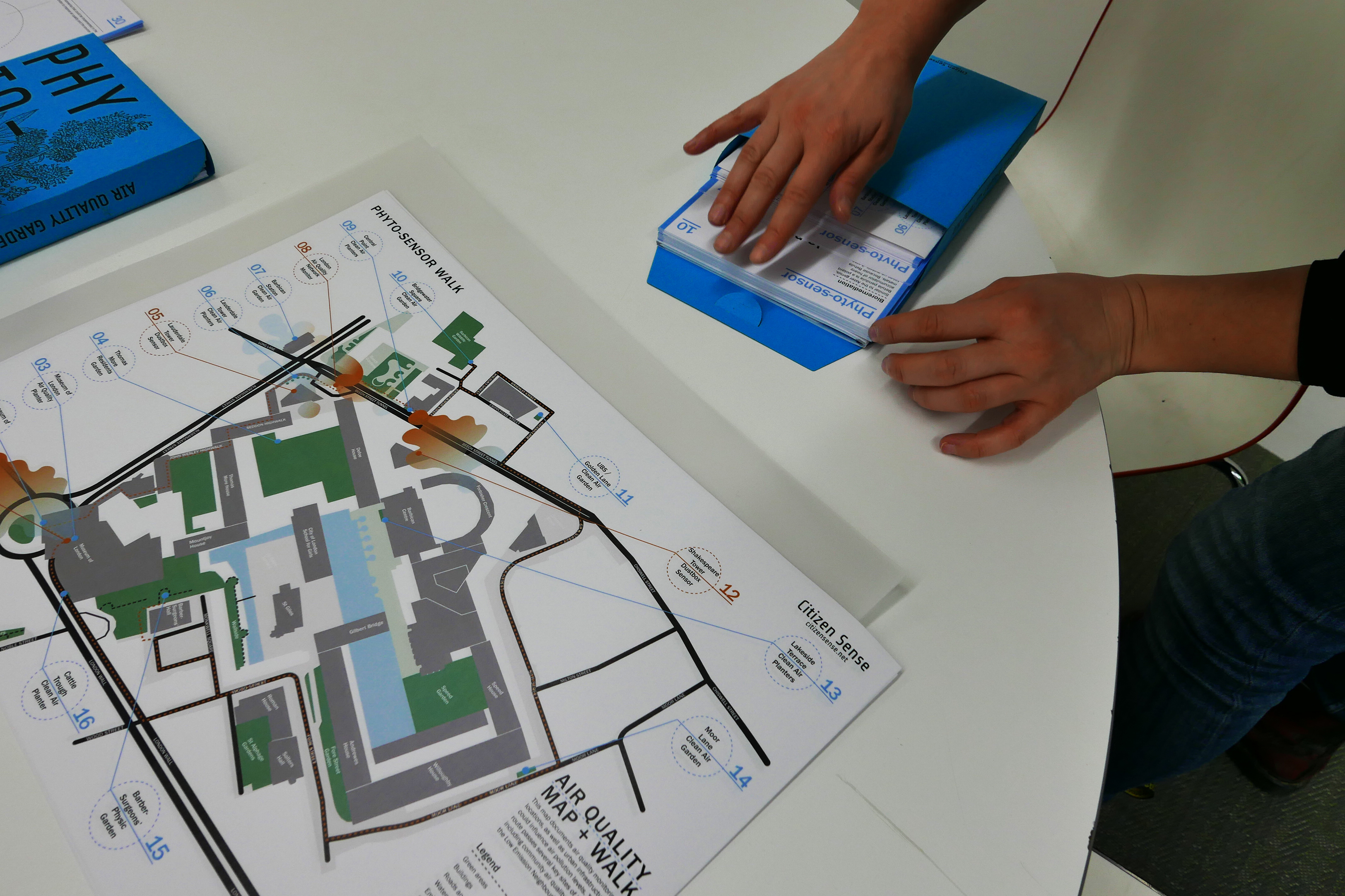 A desktop covered with a map with sixteen different named locations of interest titled “Air Quality Map and Walk” credited to Citizen Sense.