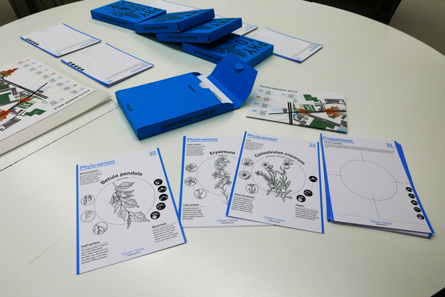 A desk topped with an array of blue boxes labeled “Phyto-senor,” each containing worksheets with different fauna, some of which are laid out.