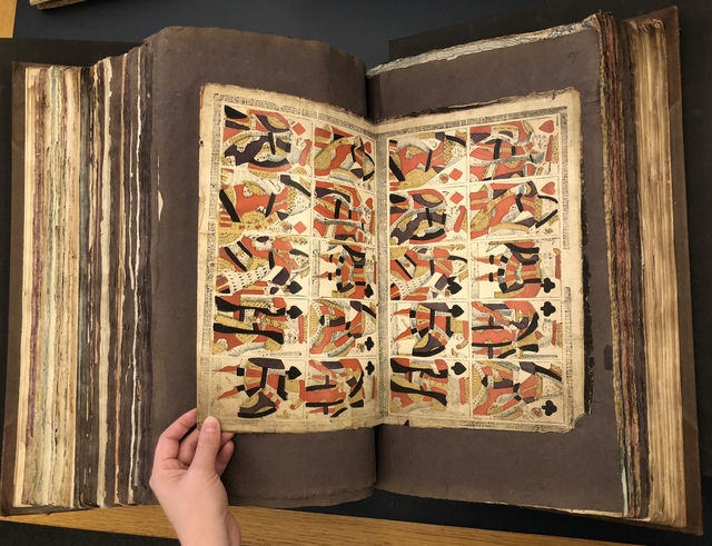Photograph of a set of uncut playing cards pasted into a large volume of paper specimens