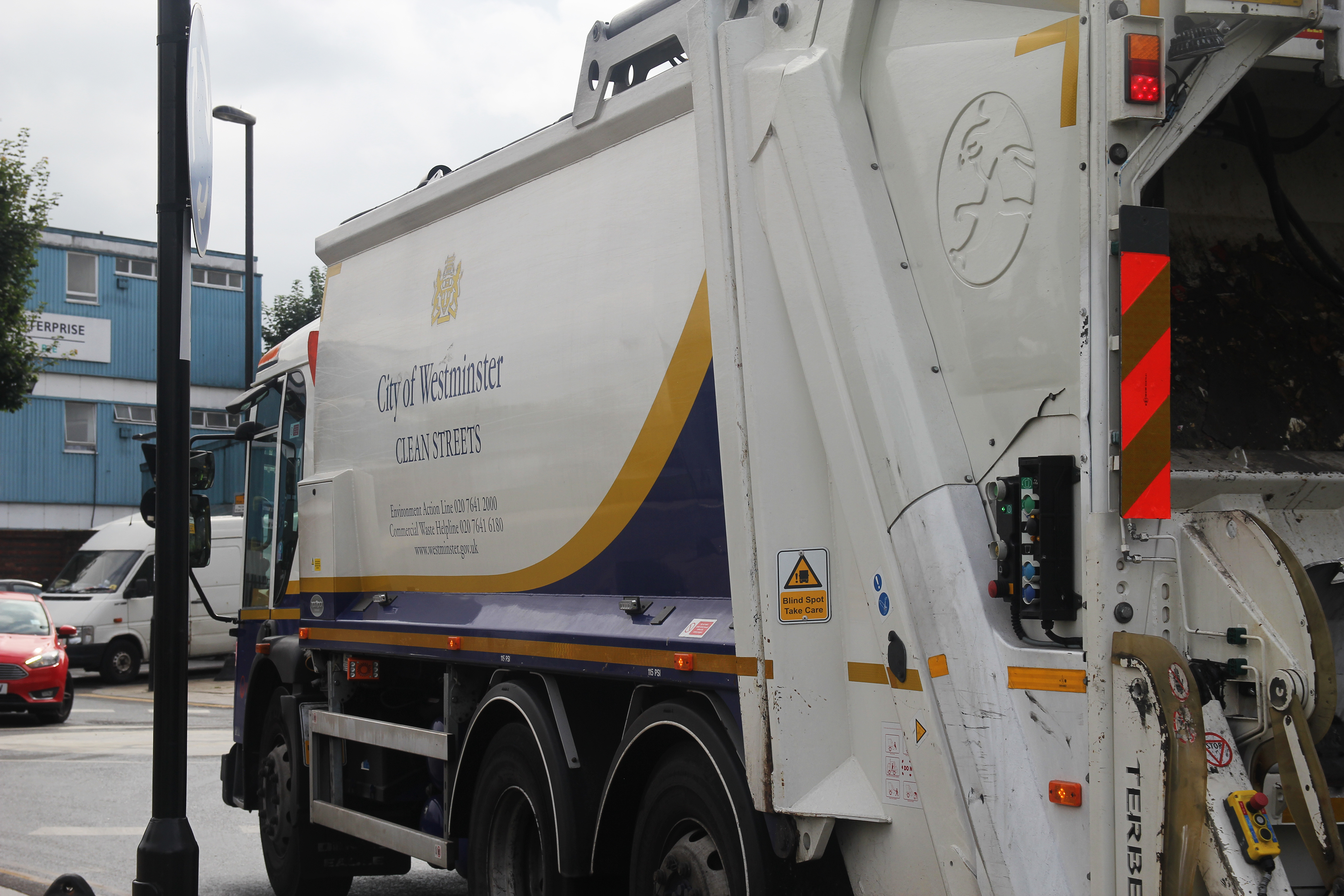 A garbage truck labeled “City of Westminster Clean Streets” on a city street.