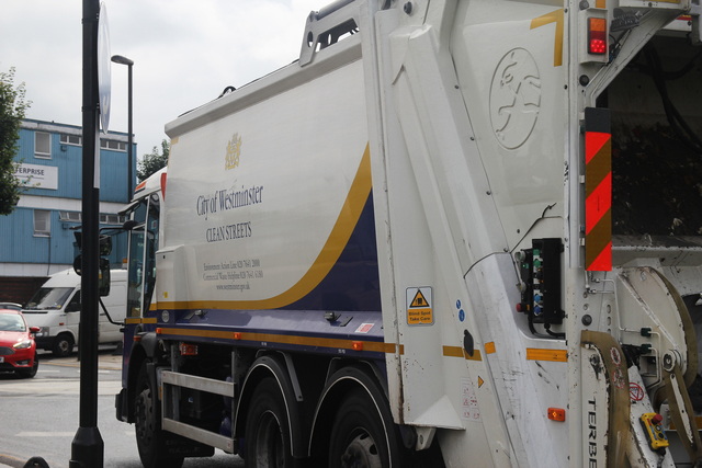 A garbage truck labeled “City of Westminster Clean Streets” on a city street.
